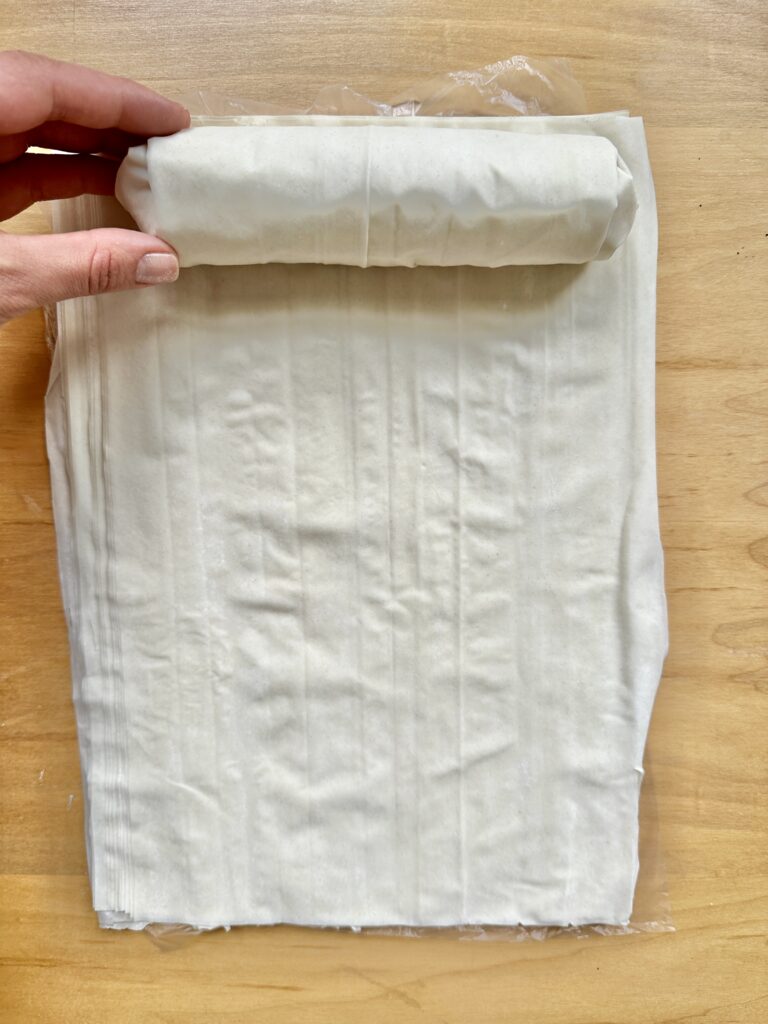 Roll fully wrapped and at the top of the photo while a hand holds it in place