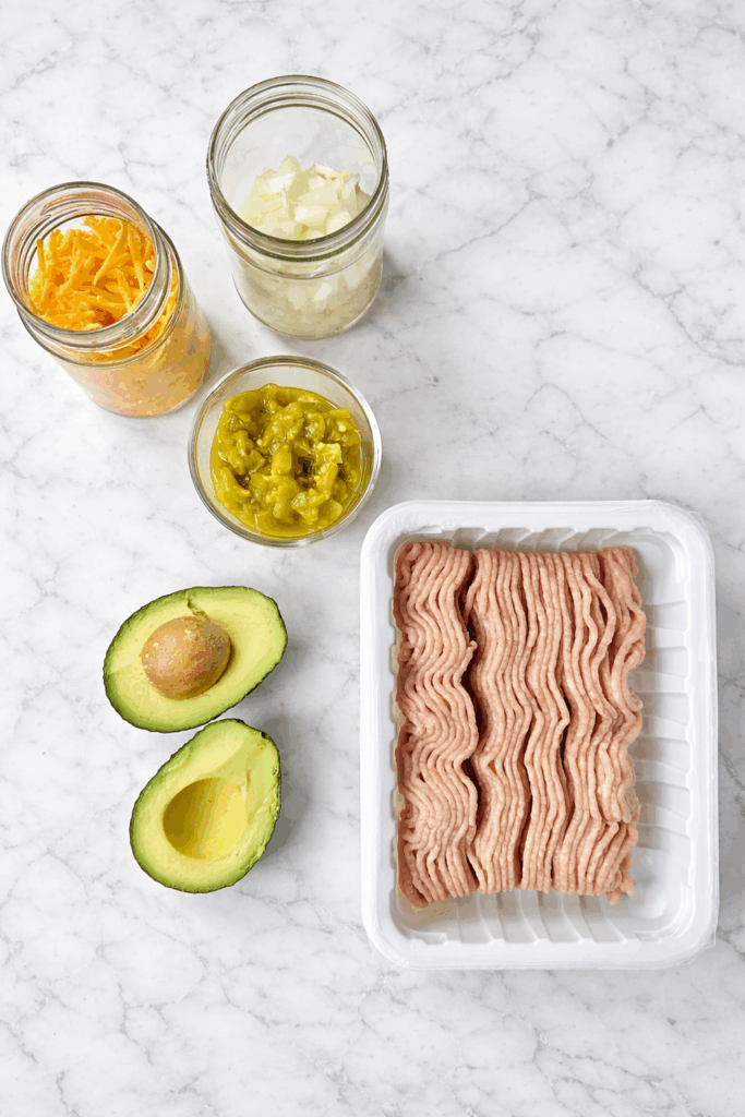 ground chicken, onion, green chilis, cheese and avocados on a marble table